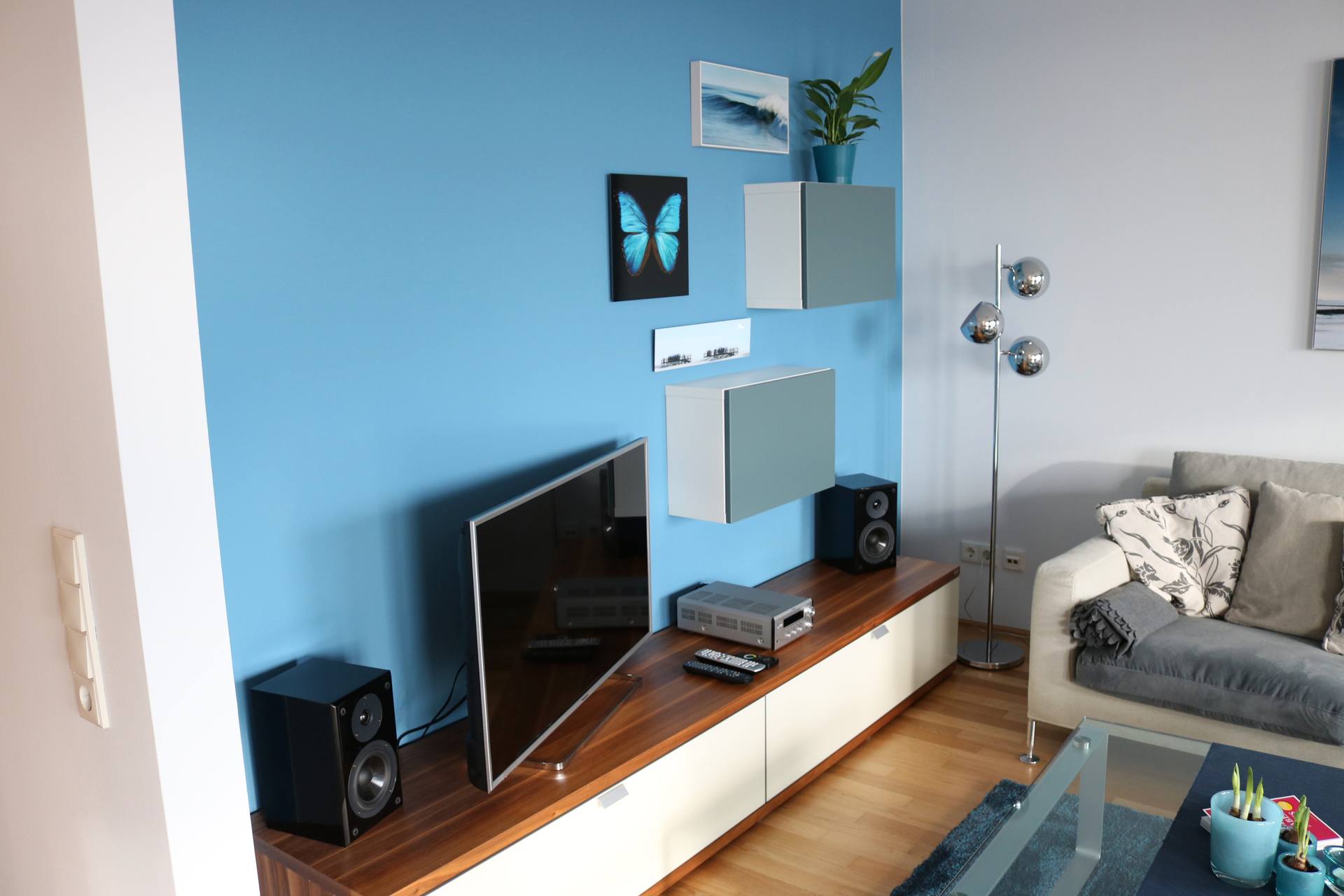 Wohnzimmer mit himmelblau gestrichener Wand und hellen Möbeln