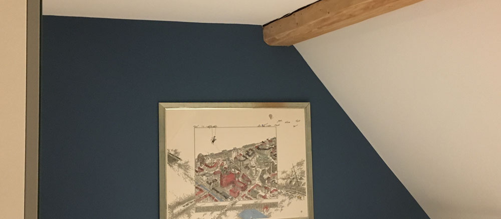 Dachschräge mit dunkelblauer Wand, Holzbalken und gerahmtem Stadtplan